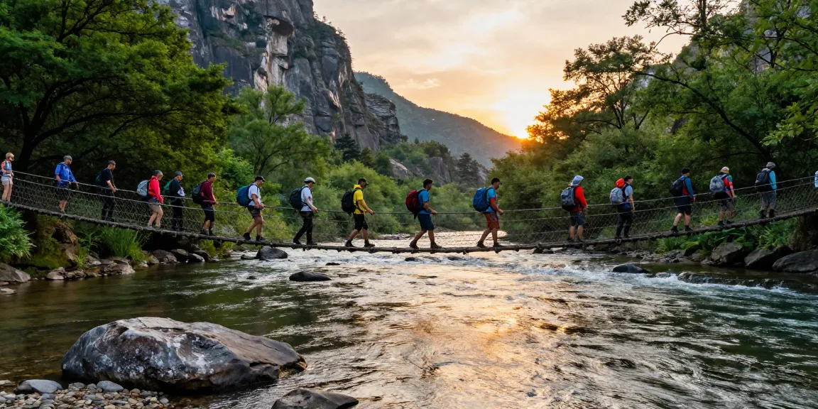Group of hikers crossing a scenic river rope bridge amidst nature's beauty during sunset.
